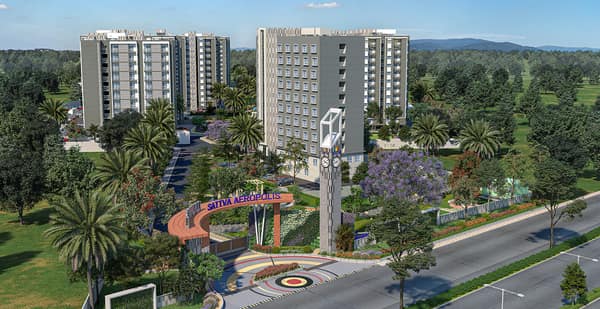 Sattva Aeropolis entrance road with the clock tower and the blocks behind, artist's impression