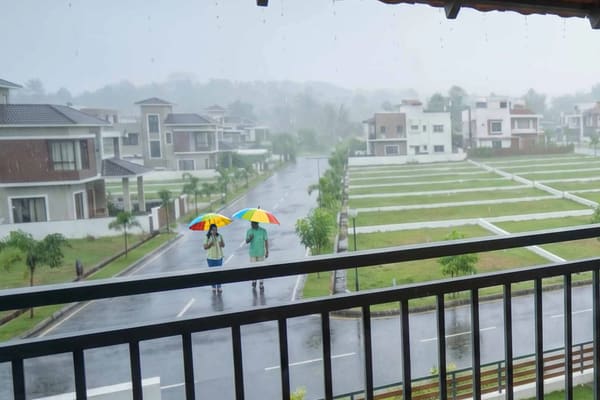 Two people with umbrellas on a plot road in the rain, seen from a balcony, artist's impression